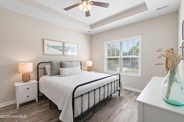 109 SW 17th St, Oak Island, NC 28465 - bedroom featuring a raised ceiling, wood finished floors, and a ceiling fan