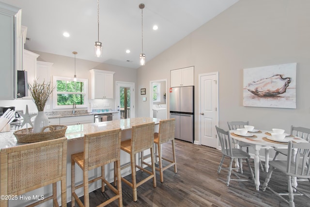 109 SW 17th St, Oak Island, NC 28465 - kitchen with stainless steel appliances, washer / dryer, a kitchen breakfast bar, white cabinets, and recessed lighting