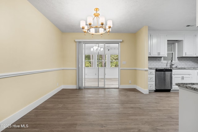 383 Red Fox St NW, Shallotte, NC 28470 - kitchen featuring stainless steel dishwasher, a chandelier, white cabinetry, tasteful backsplash, and wood finished floors