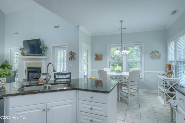 107 Sea Turtle Cv, Sneads Ferry, NC 28460 - kitchen with light tile patterned flooring, a chandelier, white cabinetry, dark stone countertops, and a fireplace