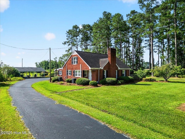 view of front of house with brick siding, a chimney, and a front yard
