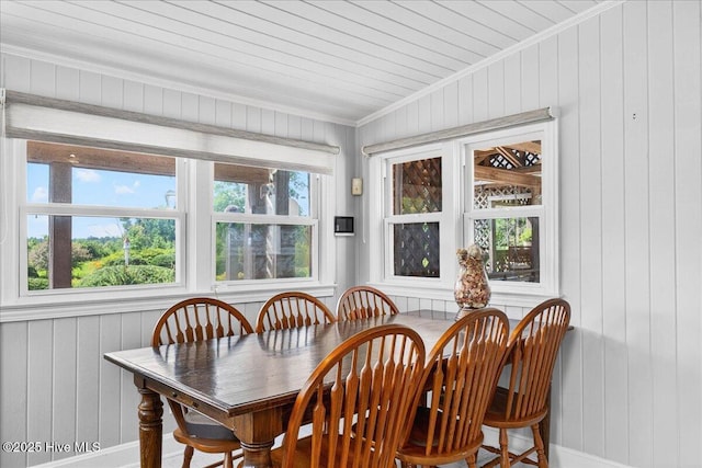 dining room with wood walls and ornamental molding