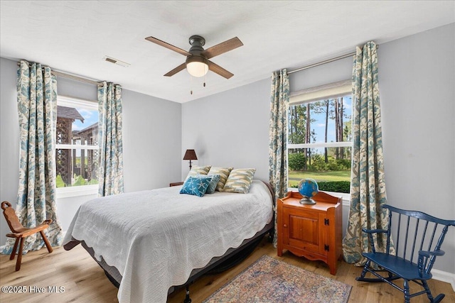 bedroom featuring multiple windows, wood finished floors, and a ceiling fan