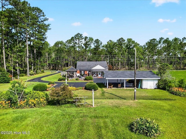 view of front facade with a front lawn and view of wooded area