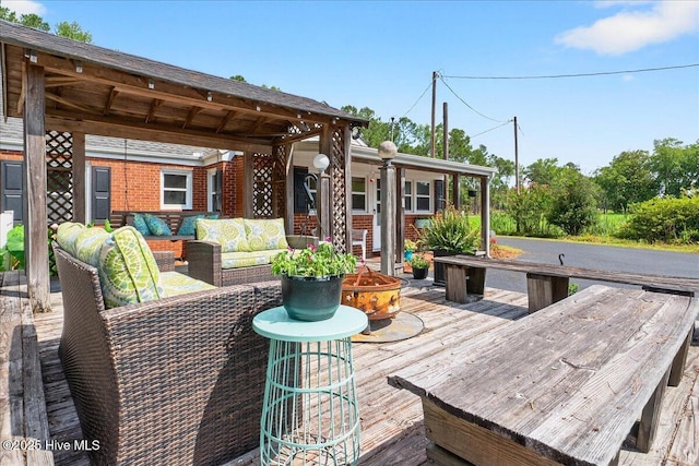 wooden terrace with an outdoor living space with a fire pit