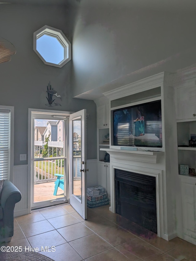 7 Oleander Ln, Ocean Isle Beach, NC 28469 - doorway to outside featuring tile patterned flooring, a wainscoted wall, built in features, a fireplace, and a towering ceiling