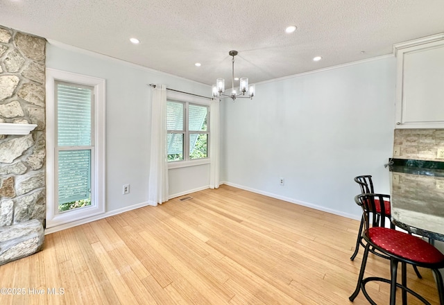 122 Ethel Dr, Emerald Isle, NC 28594 - unfurnished dining area with a chandelier, a textured ceiling, crown molding, light wood-style floors, and a stone fireplace