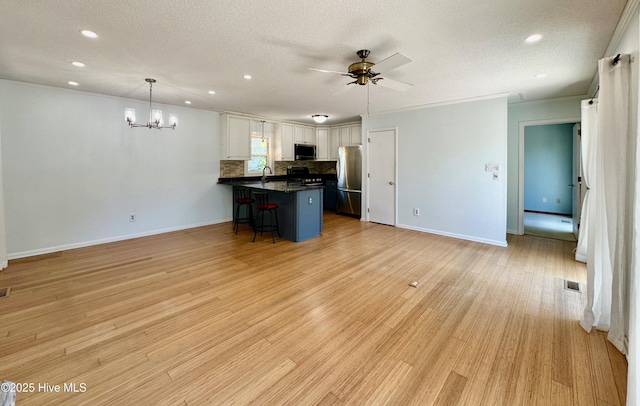 122 Ethel Dr, Emerald Isle, NC 28594 - kitchen featuring appliances with stainless steel finishes, dark countertops, a peninsula, a kitchen bar, and a chandelier