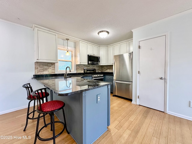 122 Ethel Dr, Emerald Isle, NC 28594 - kitchen featuring appliances with stainless steel finishes, white cabinets, a peninsula, backsplash, and a kitchen bar