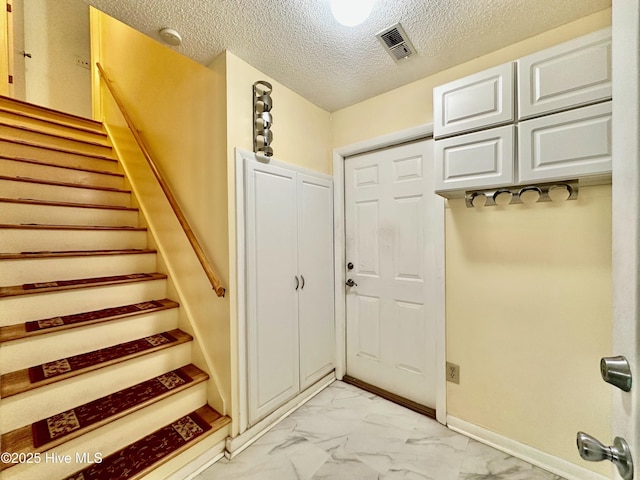 122 Ethel Dr, Emerald Isle, NC 28594 - entryway with light marble finish floors, stairs, and a textured ceiling
