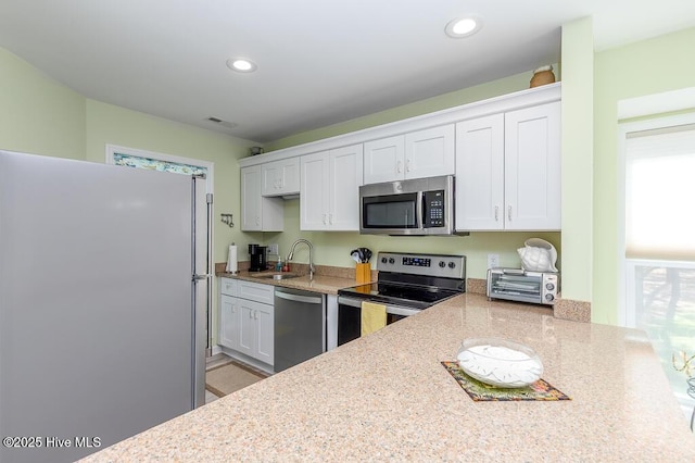 7161 Windward Dr, New Bern, NC 28560 - kitchen with appliances with stainless steel finishes, white cabinets, recessed lighting, and light stone counters