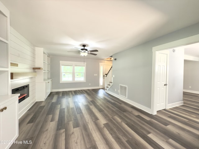 9891 Red Fox, Winnabow, NC 28479 - unfurnished living room with stairway, a ceiling fan, a fireplace, and dark wood-style flooring