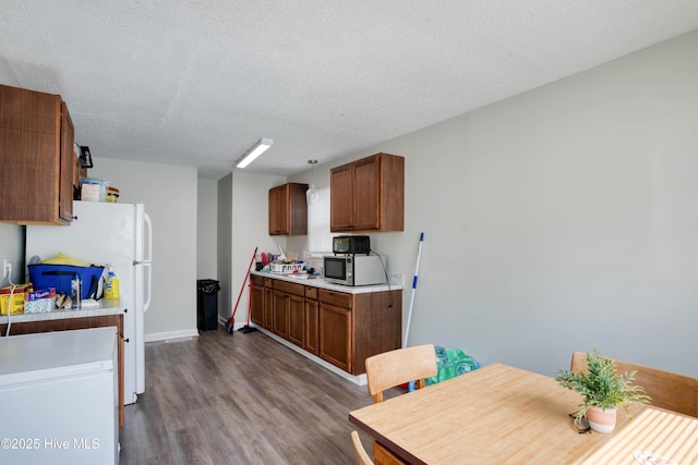 606 Anderson St, Wilmington, NC 28401 - kitchen with light countertops, dark wood-type flooring, stainless steel microwave, brown cabinets, and a textured ceiling