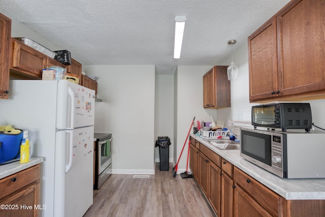 606 Anderson St, Wilmington, NC 28401 - kitchen with appliances with stainless steel finishes, light countertops, light wood-type flooring, brown cabinets, and a textured ceiling
