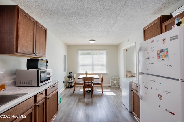 606 Anderson St, Wilmington, NC 28401 - kitchen with freestanding refrigerator, wood finished floors, light countertops, stainless steel microwave, and a textured ceiling