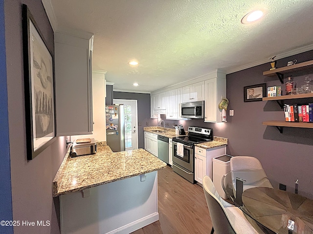 735 N Bennett St Unit A, Southern Pines, NC 28387 - kitchen with stainless steel appliances, wood finished floors, white cabinets, light stone counters, and crown molding