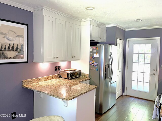 735 N Bennett St Unit A, Southern Pines, NC 28387 - kitchen with stainless steel fridge with ice dispenser, wood finished floors, light stone counters, a peninsula, and a kitchen bar