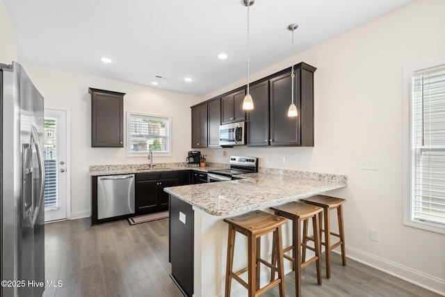 1620 Bratton Ct, Wilmington, NC 28405 - kitchen with stainless steel appliances, a peninsula, light wood-style flooring, a kitchen bar, and dark brown cabinets