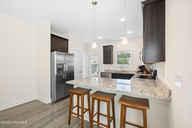 1620 Bratton Ct, Wilmington, NC 28405 - kitchen with stainless steel appliances, a peninsula, dark brown cabinetry, light wood-style floors, and light stone countertops