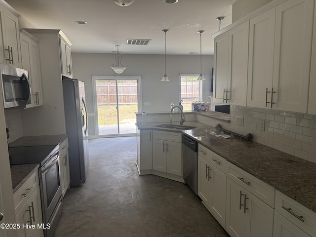 600 Burning Tree Rd, Pinehurst, NC 28374 - kitchen featuring appliances with stainless steel finishes, concrete floors, backsplash, a peninsula, and white cabinets