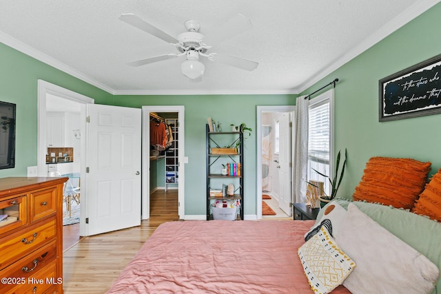 2827 Sapling Cir, Wilmington, NC 28411 - bedroom with a walk in closet, light wood-type flooring, crown molding, a closet, and a textured ceiling