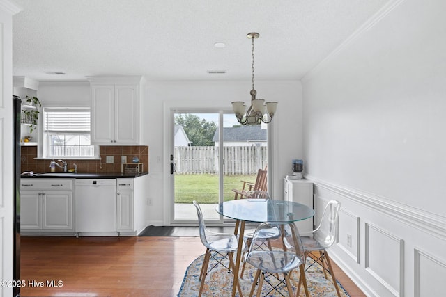 2827 Sapling Cir, Wilmington, NC 28411 - dining area featuring a chandelier, crown molding, healthy amount of natural light, wood finished floors, and a textured ceiling