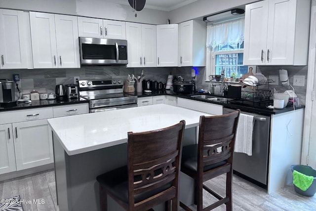 2903 Cedar Creek Rd Apt B, Greenville, NC 27834 - kitchen featuring stainless steel appliances, crown molding, a breakfast bar, light wood-style floors, and decorative backsplash