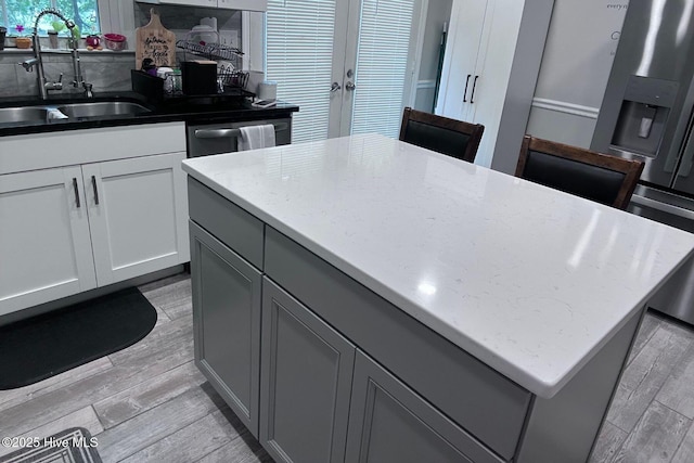 2903 Cedar Creek Rd Apt B, Greenville, NC 27834 - kitchen featuring gray cabinetry, light wood-type flooring, french doors, a center island, and light stone countertops