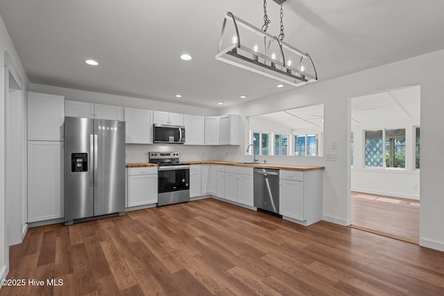 108 NW 29th St, Oak Island, NC 28465 - kitchen with stainless steel appliances, dark wood-style floors, white cabinetry, recessed lighting, and pendant lighting