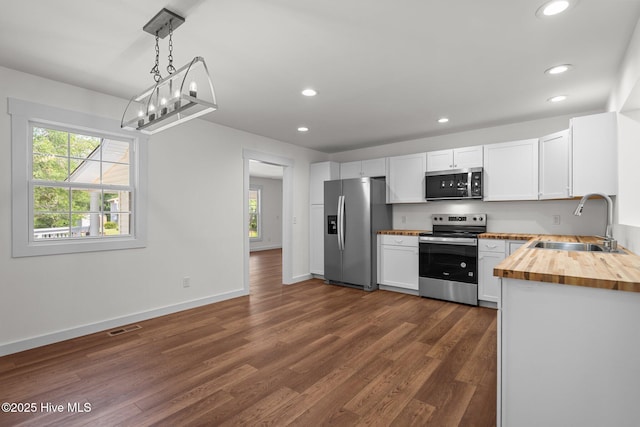 108 NW 29th St, Oak Island, NC 28465 - kitchen with appliances with stainless steel finishes, wood counters, recessed lighting, healthy amount of natural light, and dark wood-style flooring