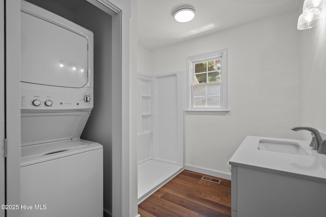 108 NW 29th St, Oak Island, NC 28465 - laundry room featuring stacked washer / dryer and dark wood-style floors