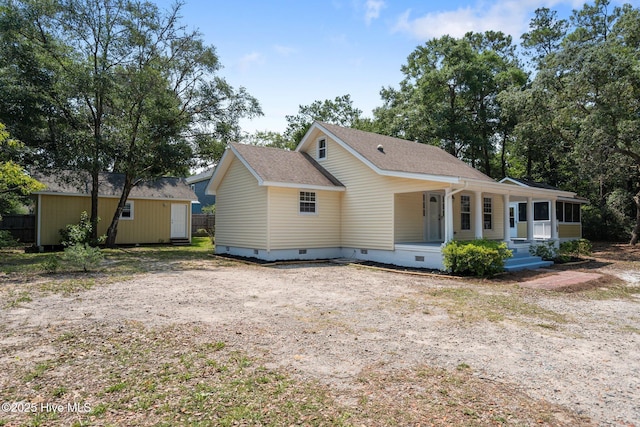 108 NW 29th St, Oak Island, NC 28465 - view of front of home featuring crawl space, covered porch, roof with shingles, and a storage shed