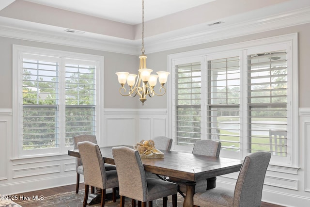 9385 Fallen Pear Ln NE, Leland, NC 28451 - dining area with a chandelier, a decorative wall, wainscoting, dark wood finished floors, and ornamental molding