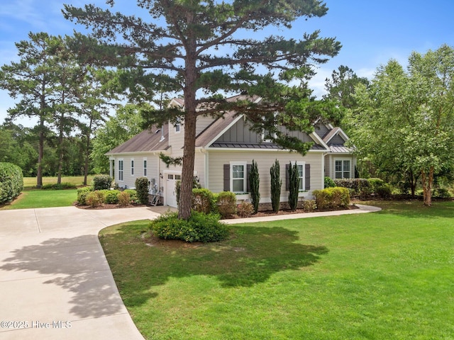 9385 Fallen Pear Ln NE, Leland, NC 28451 - view of front facade with board and batten siding, a standing seam roof, concrete driveway, a front yard, and a metal roof