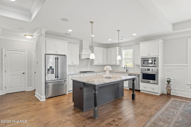 9385 Fallen Pear Ln NE, Leland, NC 28451 - kitchen featuring stainless steel appliances, premium range hood, white cabinetry, a kitchen island, and a kitchen bar