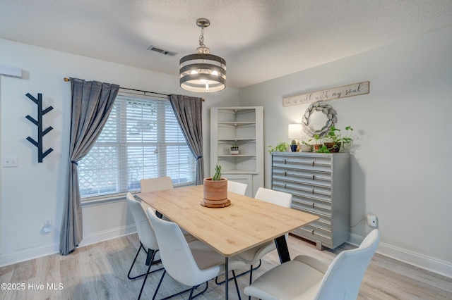 660 Pine Branches Cir SE, Leland, NC 28451 - dining area with a chandelier, light wood-style floors, and a textured ceiling