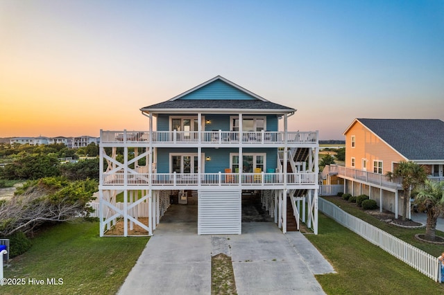 6626 W Beach Dr, Oak Island, NC 28465 - beach home with a carport, concrete driveway, a yard, stairway, and a shingled roof
