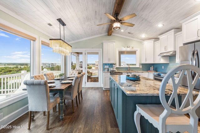 6626 W Beach Dr, Oak Island, NC 28465 - kitchen with under cabinet range hood, wood ceiling, appliances with stainless steel finishes, healthy amount of natural light, and recessed lighting