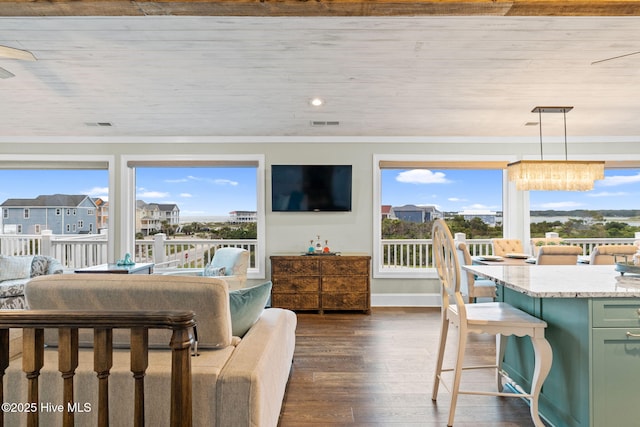 6626 W Beach Dr, Oak Island, NC 28465 - living area featuring plenty of natural light, dark wood-style floors, a chandelier, and ornamental molding