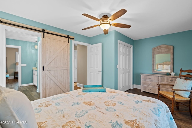 6626 W Beach Dr, Oak Island, NC 28465 - bedroom with a barn door, a closet, dark wood-style flooring, and ceiling fan