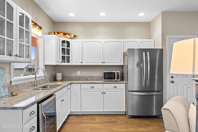 6626 W Beach Dr, Oak Island, NC 28465 - kitchen with stainless steel appliances, wine cooler, white cabinets, light stone counters, and wood finished floors