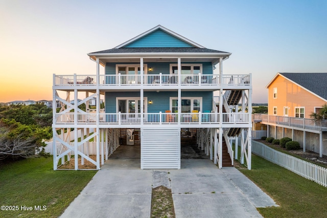6626 W Beach Dr, Oak Island, NC 28465 - raised beach house featuring driveway, stairway, a carport, and a front lawn