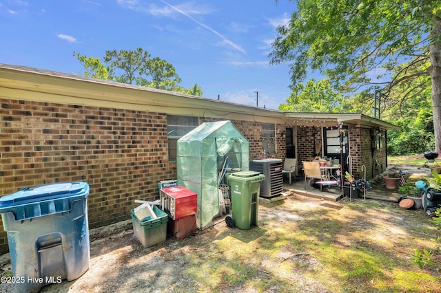 view of side of property featuring brick siding and a cooling unit