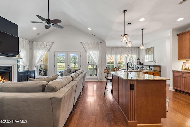 3710 Calla Lilly Ct, Southport, NC 28461 - kitchen with open floor plan, brown cabinets, a ceiling fan, a breakfast bar, and light stone countertops