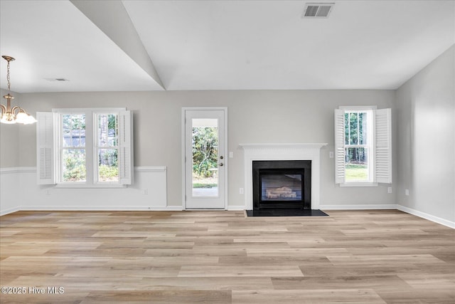 111 Yaupon Ct, Hampstead, NC 28443 - unfurnished living room featuring a chandelier, light wood-style floors, a fireplace with flush hearth, and vaulted ceiling