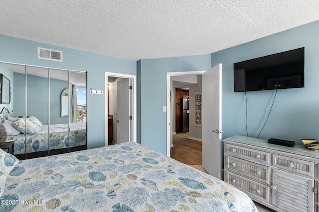 2000 New River Inlet Rd Unit 3513, North Topsail Beach, NC 28460 - bedroom featuring wood finished floors, a textured ceiling, a closet, and freestanding refrigerator