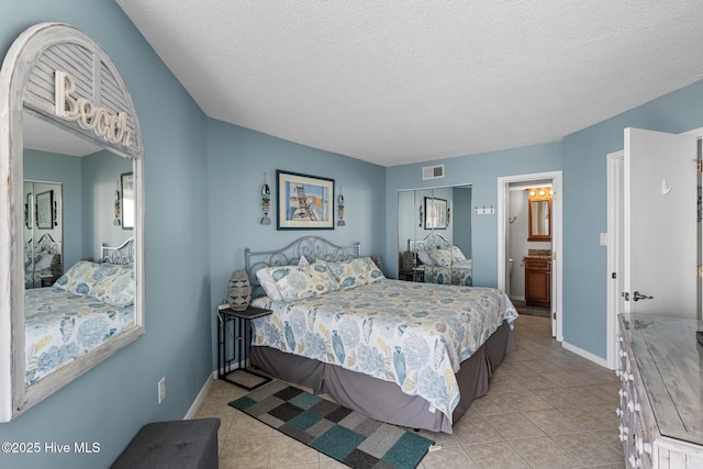 2000 New River Inlet Rd Unit 3513, North Topsail Beach, NC 28460 - bedroom featuring light tile patterned flooring, a textured ceiling, and ensuite bath