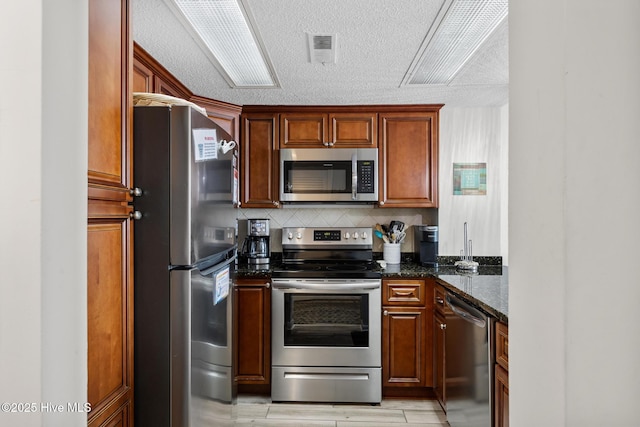 2000 New River Inlet Rd Unit 3513, North Topsail Beach, NC 28460 - kitchen with stainless steel appliances, dark stone countertops, a textured ceiling, and tasteful backsplash