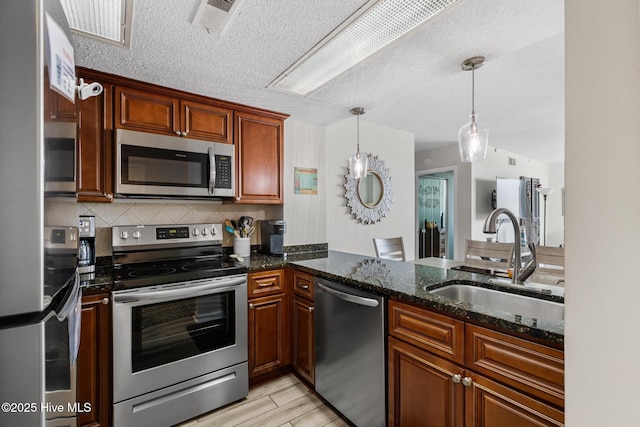 2000 New River Inlet Rd Unit 3513, North Topsail Beach, NC 28460 - kitchen featuring stainless steel appliances, decorative light fixtures, dark stone countertops, light wood-style floors, and tasteful backsplash