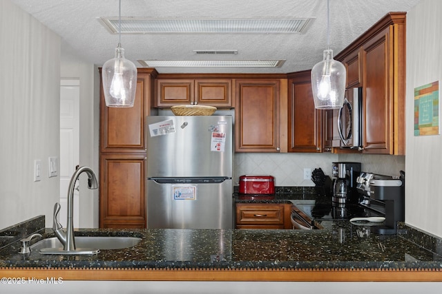 2000 New River Inlet Rd Unit 3513, North Topsail Beach, NC 28460 - kitchen featuring appliances with stainless steel finishes, dark stone countertops, a textured ceiling, hanging light fixtures, and tasteful backsplash